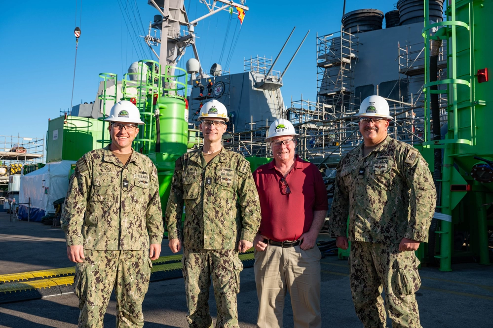 Commander, Navy Regional Maintenance Center (CNRMC) and Director, Surface Ship Maintenance, Modernization, and Sustainment (SEA21) Rear Adm. William ‘Bill’ Greene, Forward Deployed Regional Maintenance Center Commanding (FDRMC) Officer Capt. Brian Karosich, FDRMC Detachment Rota Officer in Charge Capt. Paul Murch and USS Roosevelt (DDG 80) Project Manager John Mahony pause on the pier in front the Arleigh Burke-class guided-missile destroyer Roosevelt during the ship's Selected Restricted Availability, a planned maintenance period that will ensure the ship remains fully mission-capable while forward deployed to Rota, Spain and the U.S. Sixth Fleet area of operations.