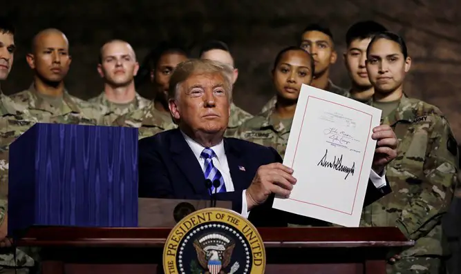 President Trump holds up the National Defense Authorization Act after signing it on Monday, August 13, 2018. The bill includes $5.5 billion to Israel.