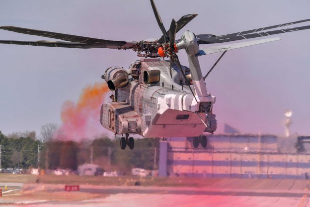 Colored oil smoke indicates rotor wake and wind effects while external â€œtuftsâ€ adhere to the outside of the CH-53K King Stallion showing surface airflow. These efforts validate a modification mitigating Exhaust Gas Re-ingestion for the new Marine Corps aircraft. US Navy photo.