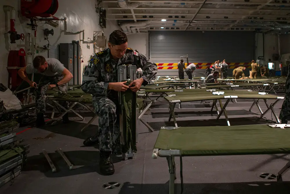 Petty Officer Marine Technician Brendan McDermott assembles stretcher beds onboard HMAS Adelaide in response to Operation BUSHFIRE ASSIST 19-20.