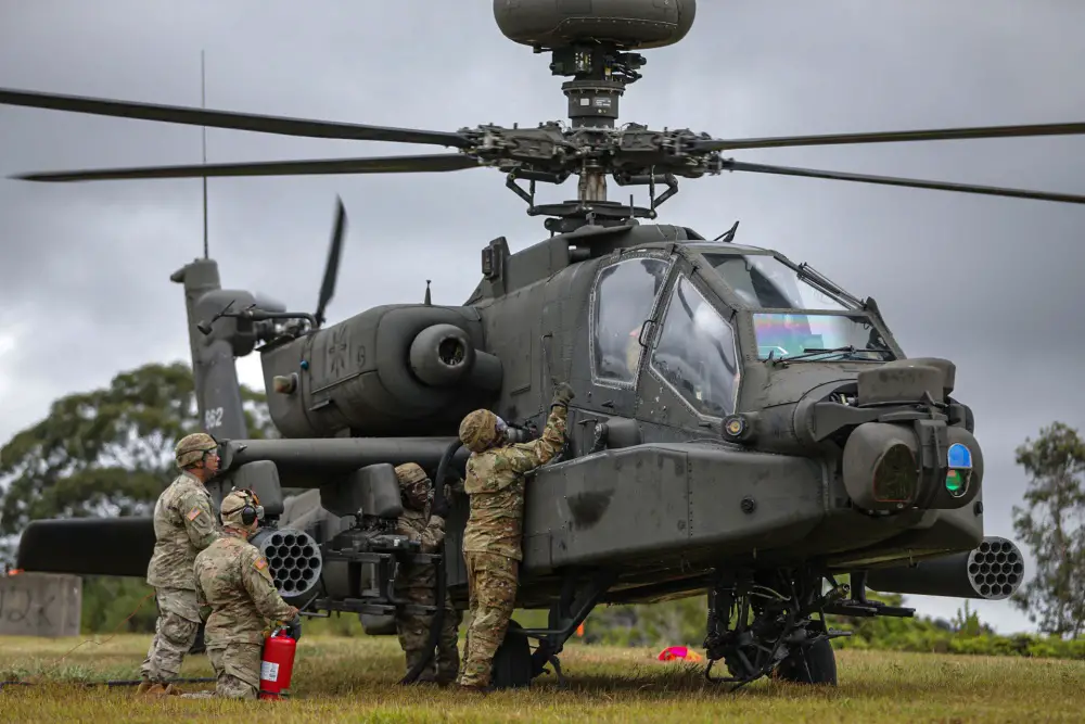 Petroleum Supply Specialists work together to refuel an Apache attack helicopter during training in FATCOW procedures.
