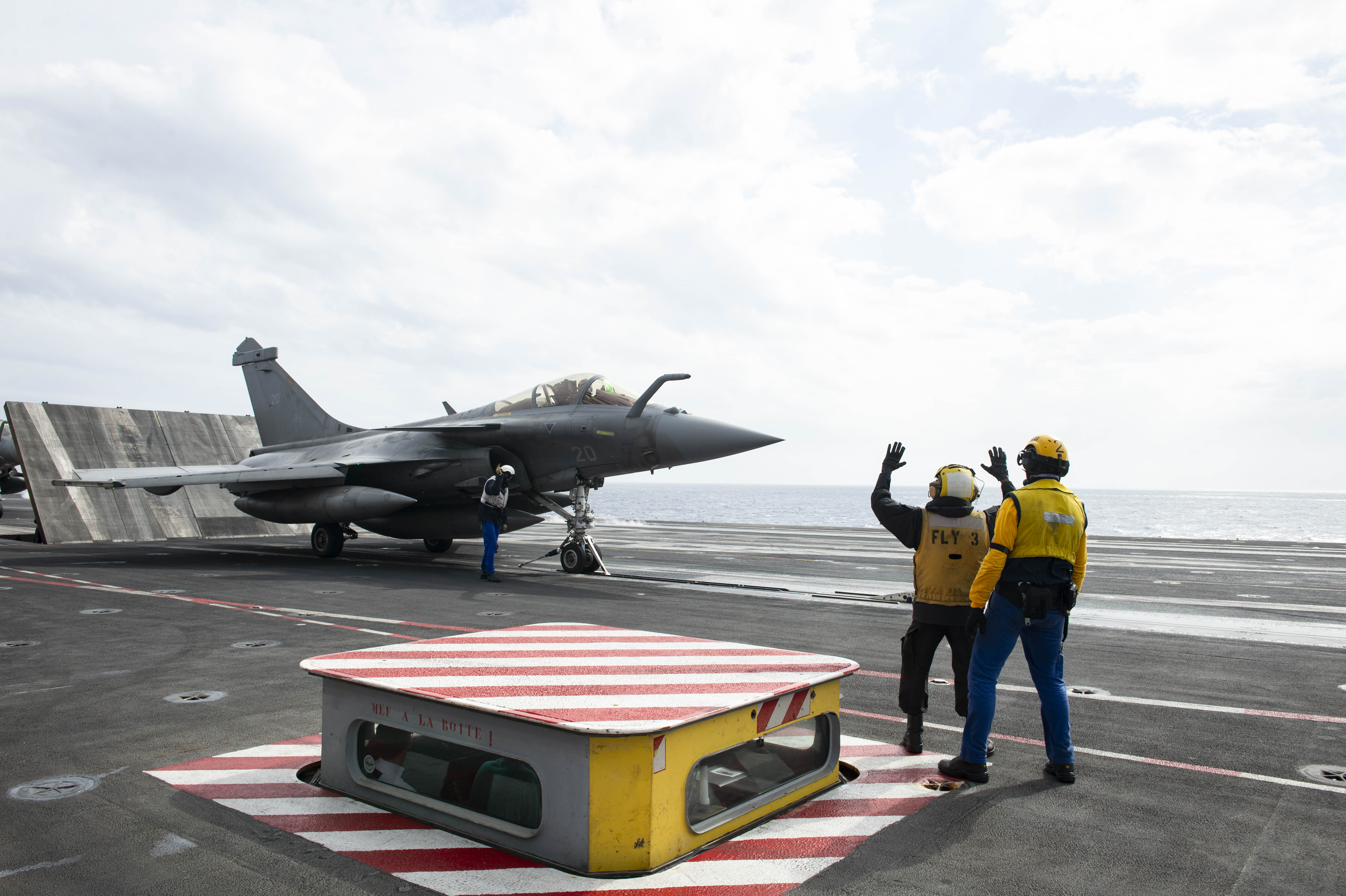 Aviation Boatswain's Mate (Handling) 3rd Class Lauret Price, from Cleveland, left, and a member of the French Marine Nationale, spot a French Dassault Rafale M fighter jet on the flight deck aboard the French aircraft carrier Charles de Gaulle (R 91) while conducting interoperability exercises with the aircraft carrier USS Dwight D. Eisenhower (CVN 69).