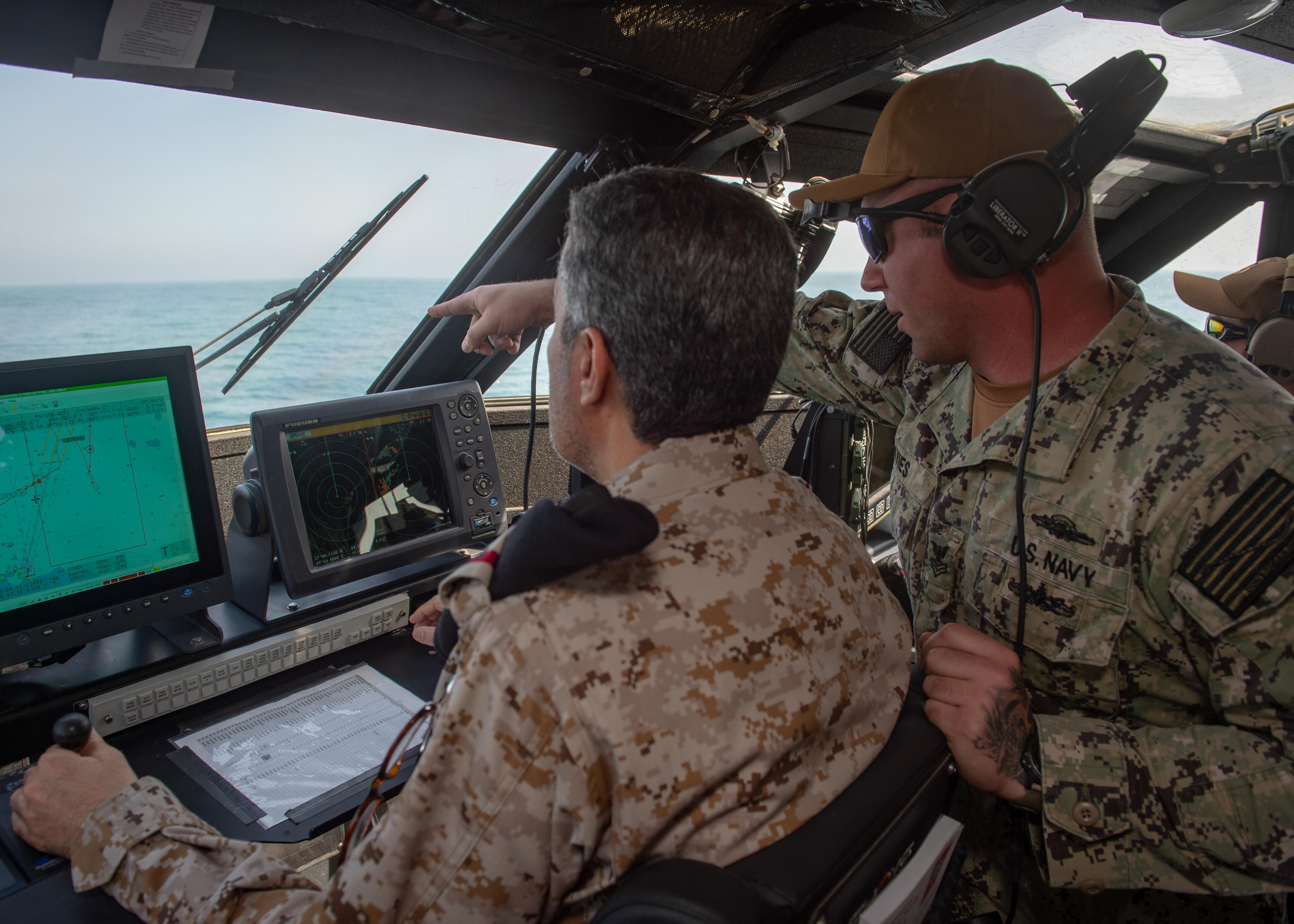 Gunner's Mate 1st Class Andrew Davies, assigned to Commander Task Force 56, guides Rear Adm. Majed Haz'z Al-Kahtani, deputy commander of Royal Saudi Naval Forces (RSNF) Eastern Fleet, on how to operate a Mark VI patrol boat during an underway as part of exercise Nautical Defender 20 in Jubail, Kingdom of Saudi Arabia, Feb. 23, 2020. 