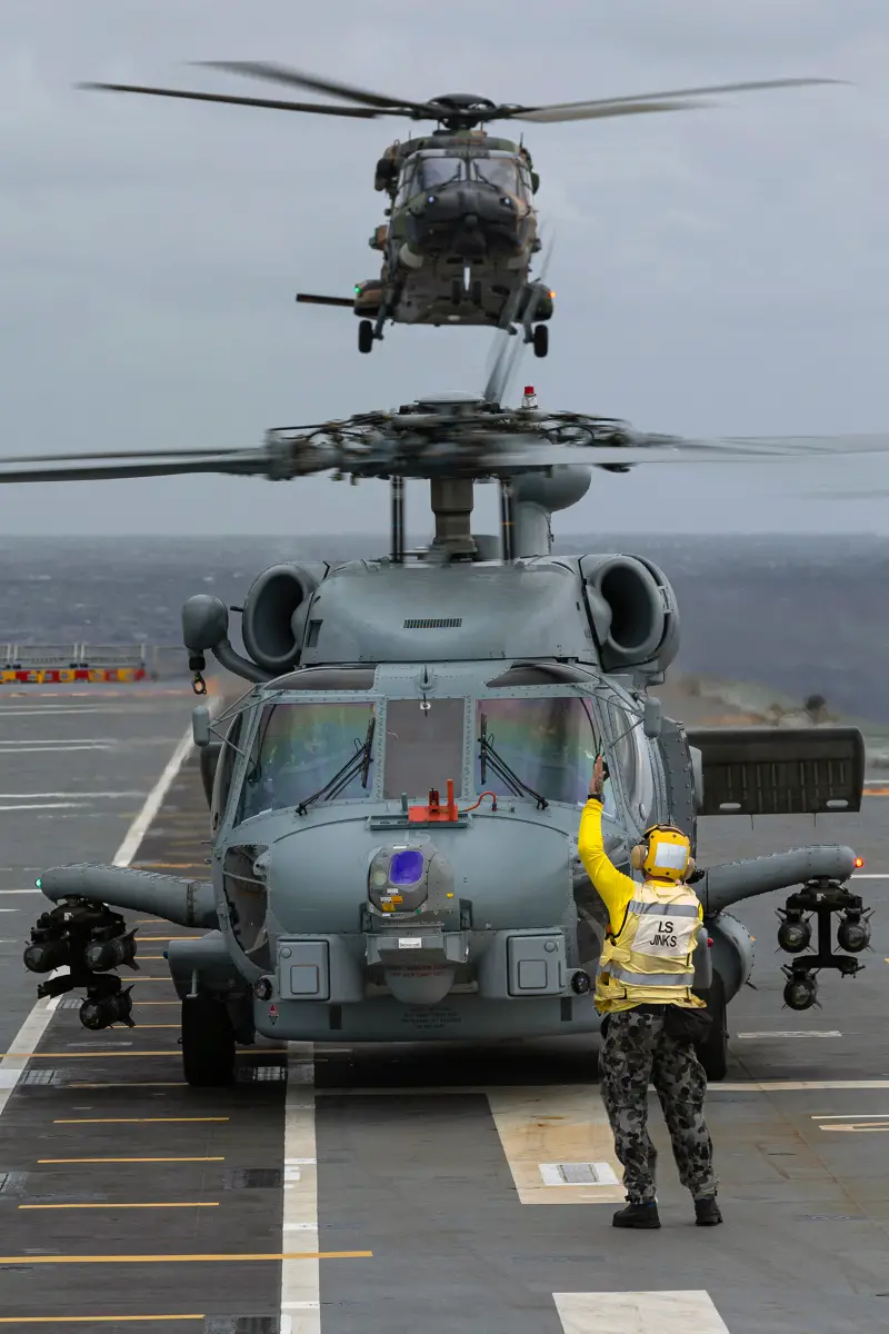 Embarked MRH-90 helicopter â€˜Midnight' prepares to land onboard HMAS Adelaide as embarked MH-60 Romeo helicopter â€˜Cobra 15' ground runs in the foreground during First of Class Flight Trials.