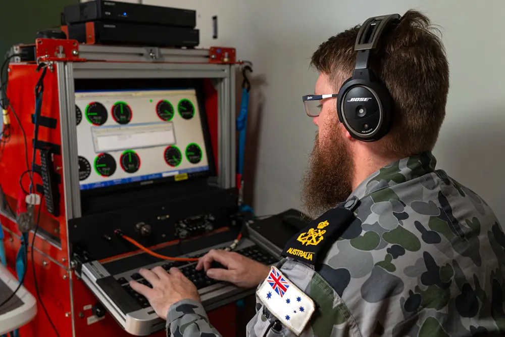 Petty Officer Aviation Technician Avionics Nicholas Simmons of the Aircraft Maintenance and Flight Trials Unit enters test flight data from an MH-60R helicopter into the computer onboard HMAS Adelaide.