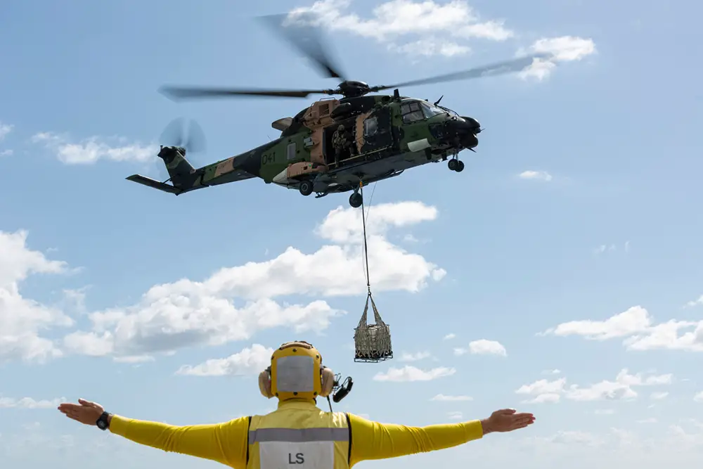 Leading Seaman Aviation Support Blake Dare marshals an MRH-90 helicopter during a vertical replenishment exercise onboard HMAS Adelaide.
