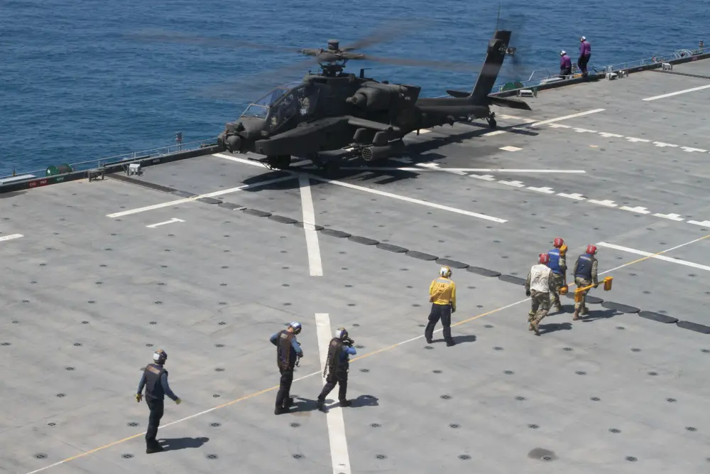 U.S. Navy deck crew gets into position to secure an AH-64E Apache gunship to the deck of the U.S.S. Lewis B. Puller during an at sea training exercise on April 16, 2020 in the Persian Gulf. The U.S. Army and the U.S. Navy work together to not only train but also make both forces more effective. (U.S. Army photo by SGT. Andrew Winchell)