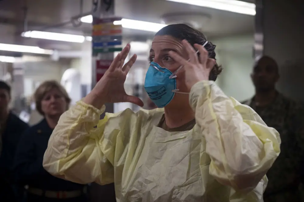 Lt. Cmdr. Nevin Yazici demonstrates how to properly fit an N95 respiratory protective device aboard hospital ship USNS Comfort (T-AH 20) as the ship prepares to admit patients in support of the nation's COVID-19 response efforts. 