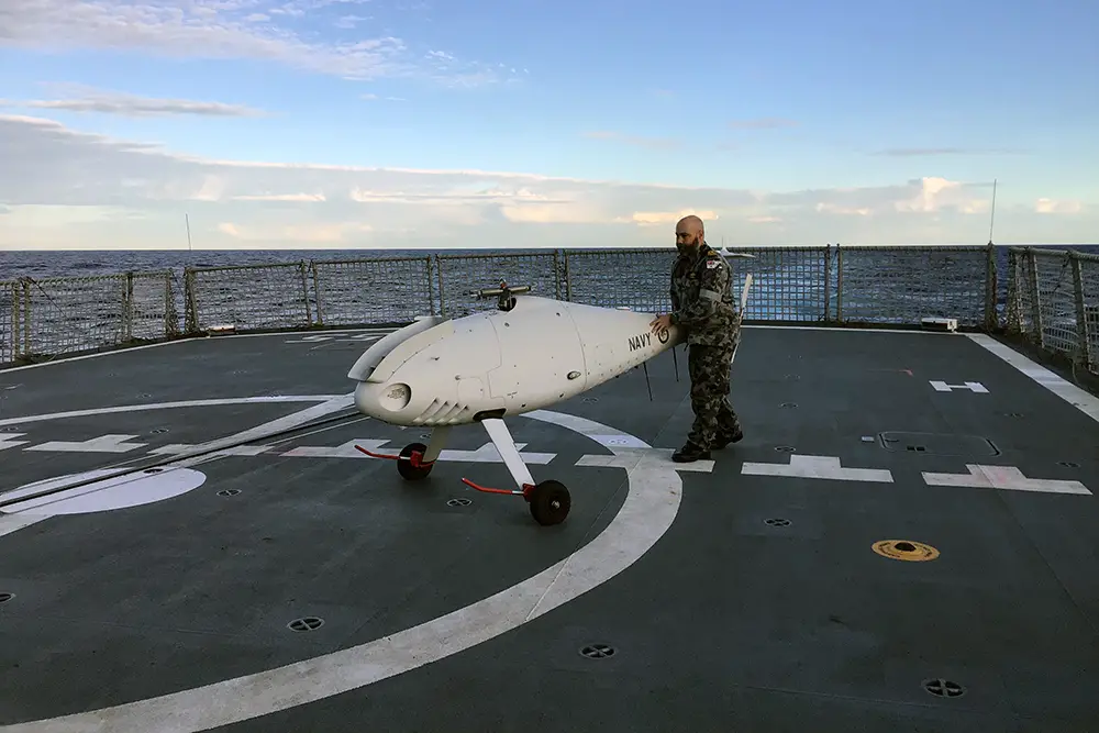 
822X Squadron Deputy Engineer Lieutenant Gareth Forbes recovers the S-100 Camcopter on HMAS Ballarat's flight deck.