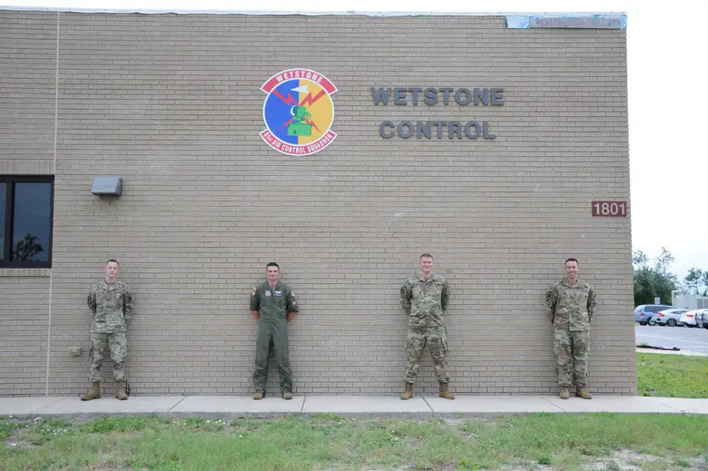 Members of the 81st ACS that planned, organized and led COMBAT Sentry stand in front of the 81st ACS patch while social distancing during the first-ever COMBAT Sentry WSEP. (U.S. Air Force photo by 1st Lt Savanah Bray)