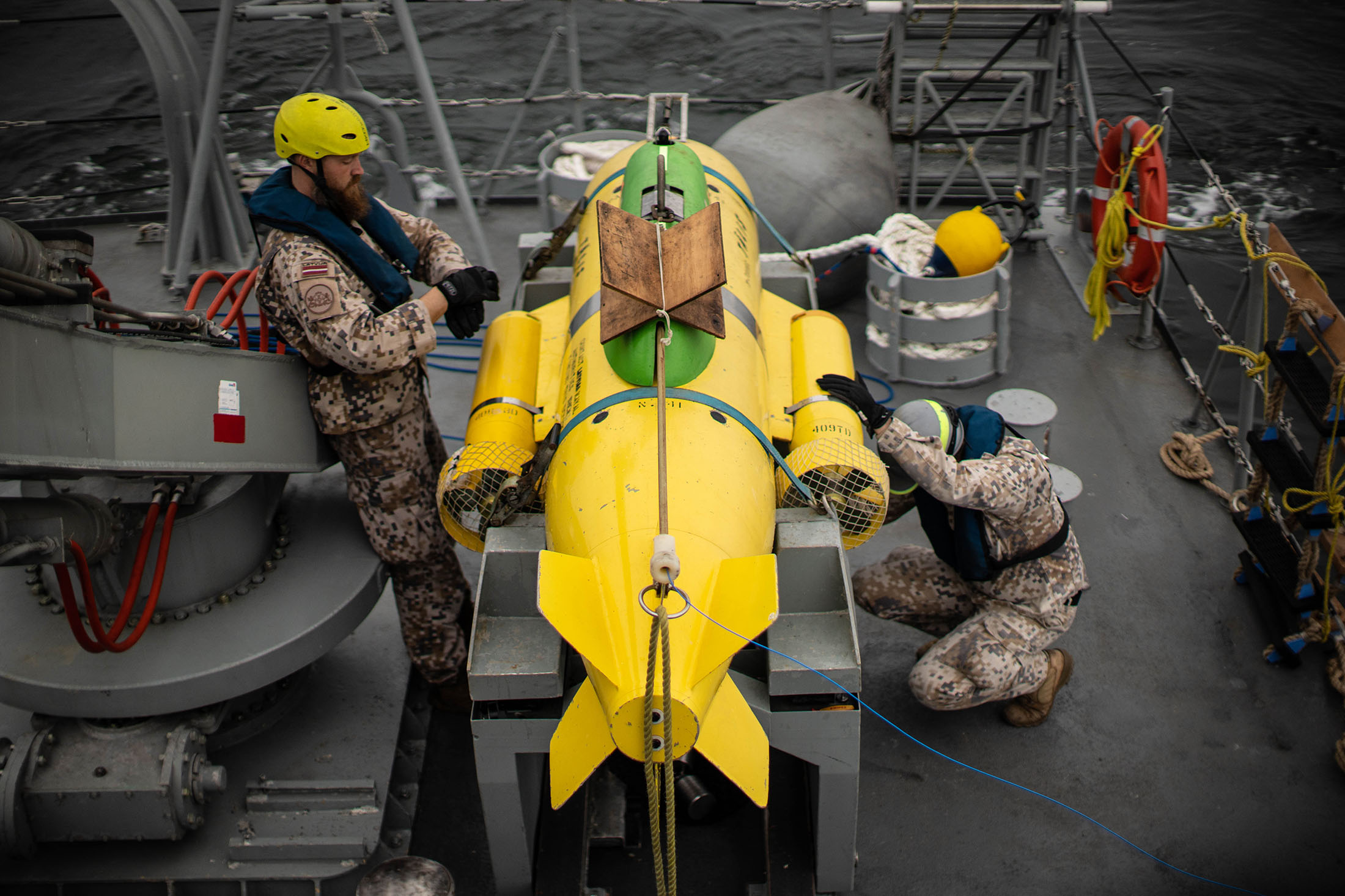 Crewmembers from the LVNS TÄlivaldis with the ship's ROV (remote operated vehicle) PAP 104, an underwater robot that helps identify and dispose of mines or unexploded ordnance.