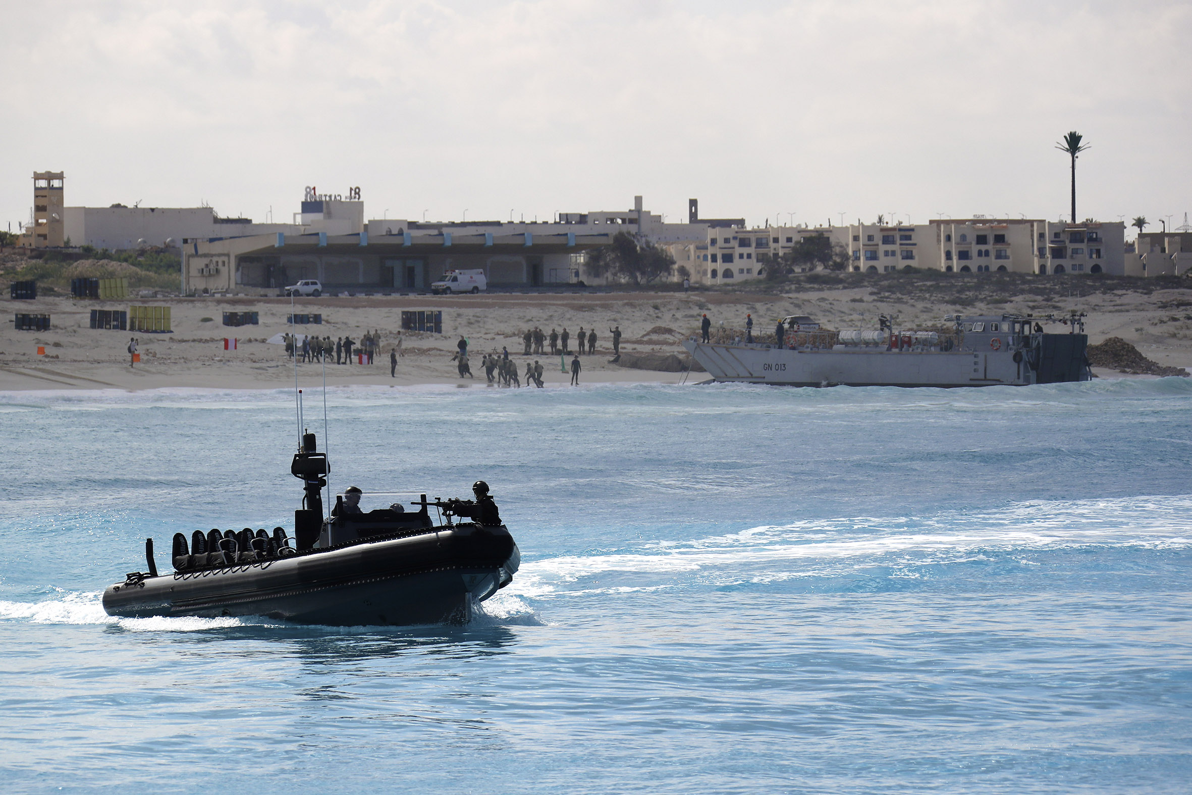 Egyptian troops come ashore by landing craft as a Royal Marines ORC patrols offshore.