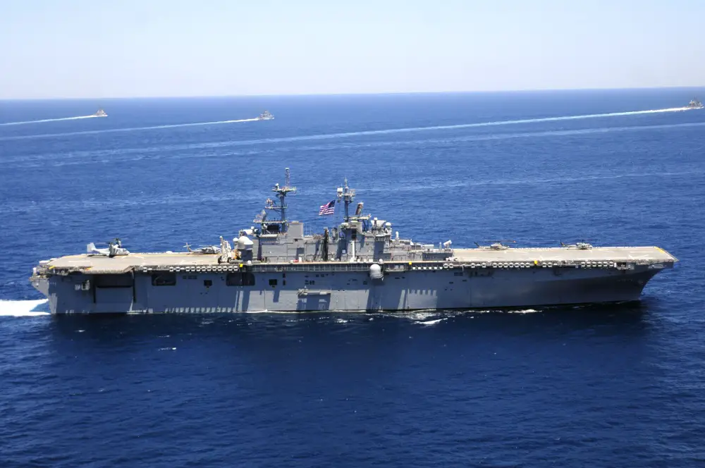 The amphibious assault ship USS Wasp transits ahead while 15 coalition partner ships break away from formation during a sailing event while participating in the War of 1812 fleet exercise.