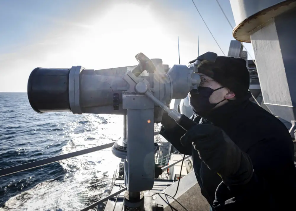 Ensign James Bateman, from Huntsville, Ala., scans the horizon utilizing the â€˜big eyes' while standing watch on the on the bridge wing as the guided-missile destroyer USS John S. McCain (DDG 56) conducts routine underway operations.