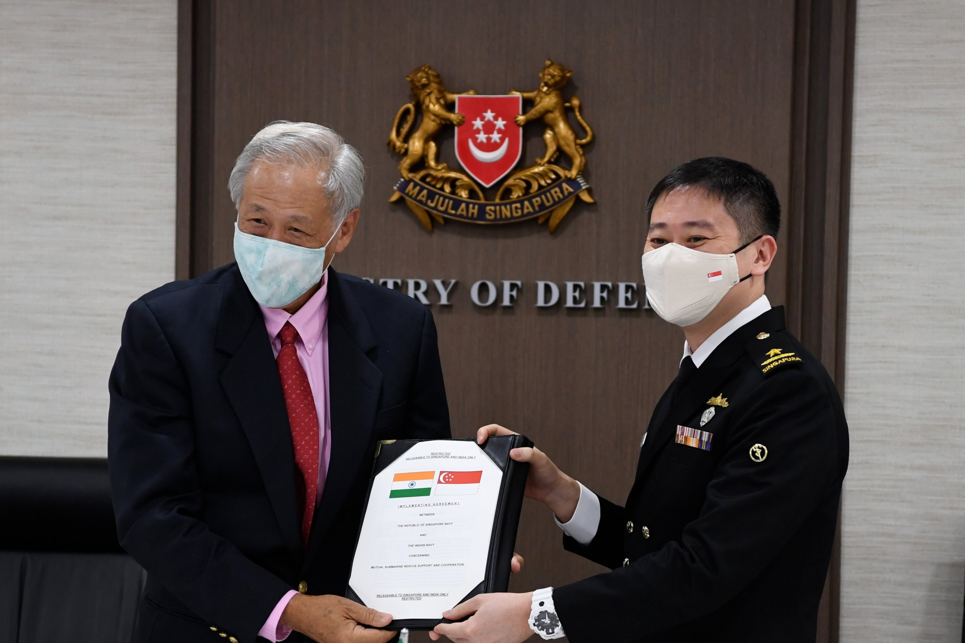 COS-NS Rear-Admiral Edwin Leong showing a signed copy of the Submarine Rescue Support and Cooperation Implementing Arrangement with Singapore Minister for Defence Dr Ng Eng Hen