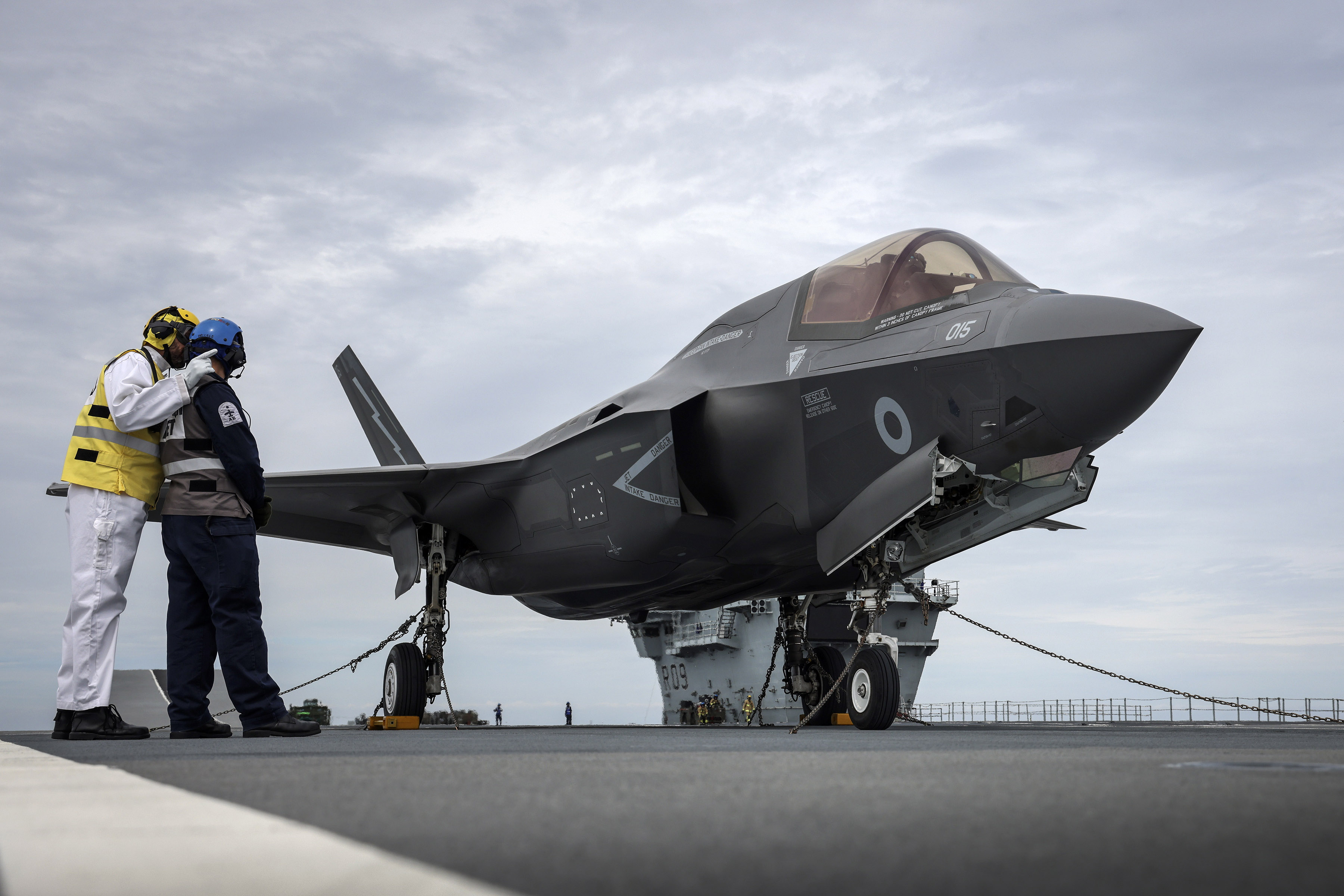 HMS Prince of Wales' Flight Deck Officer confers with an Air Engineer next to the first F-35 on deck.