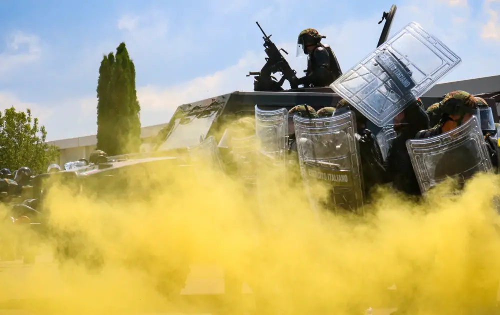 Italian Army Soldiers assigned to Regional Command-West, Kosovo Force, approach the main square through smoke during Operation Swift Rescue at the Gjakova/GjakovÃ« Airfield in Kosovo on June 10, 2021.
