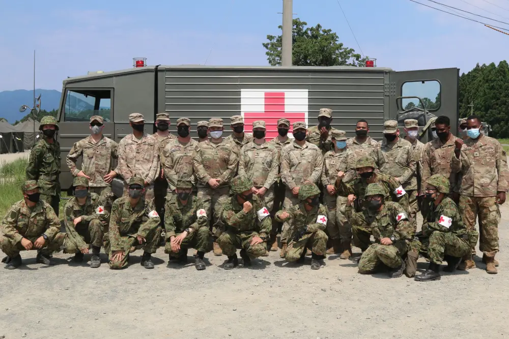 Medics assigned to 1st Battalion, 28th Infantry Regiment, 3rd Infantry Division, pose alongside medics from the Japan Ground Self-Defense Force after training on how to properly load a casualty into an ambulance during bilateral medical training on Aibano Training Area, Japan, as part of exercise Orient Shield 21-2 June 24, 2021. 