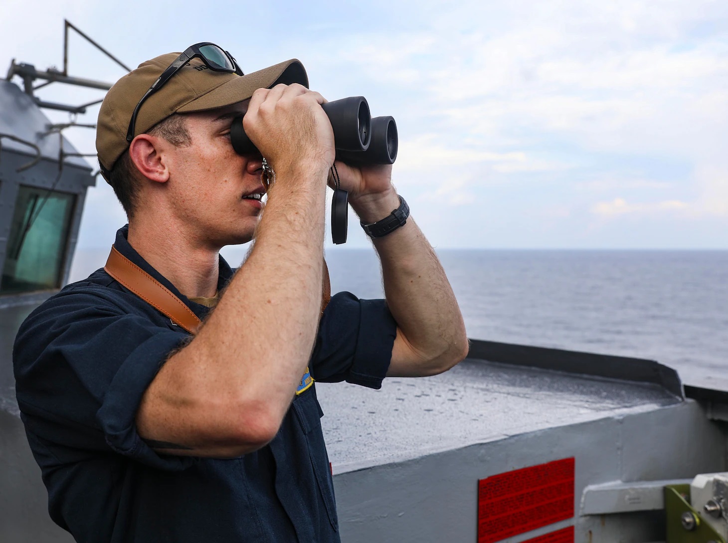 Lt.j.g. Andrew Hayne, from Parker, Colo., uses binoculars to monitor a surface contact from the bridge wing of the Arleigh Burke-class guided-missile destroyer USS Benfold (DDG 65) while conducting routine underway operations. Benfold is forward-deployed to the U.S. 7th Fleet area of operations in support of a free and open Indo-Pacific. 