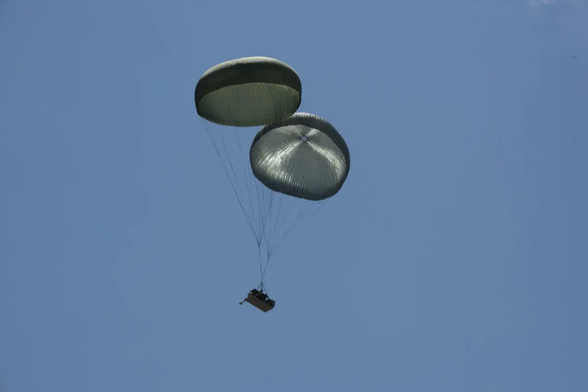 An Infantry Squad Vehicle (ISV) on a Dual Row Airdrop System (DRAS) airdrop descends above Holland Drop Zone at Fort Bragg, North Carolina under two G-11D cargo parachutes during operational testing.