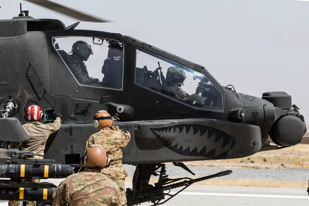 Petroleum Supply Specialists work together to refuel an AH-64E Apache attack helicopter.