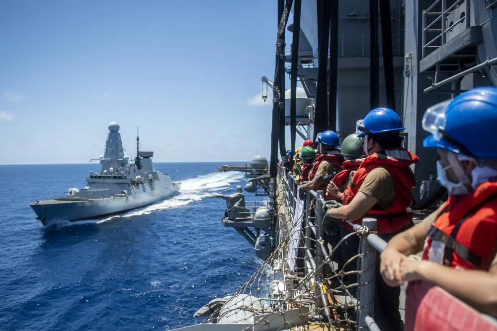 Sailors assigned to the forward-deployed amphibious assault ship USS America (LHA 6), man the rails before a fueling-at-sea with Royal Navy destroyer HMS Defender (D36).
