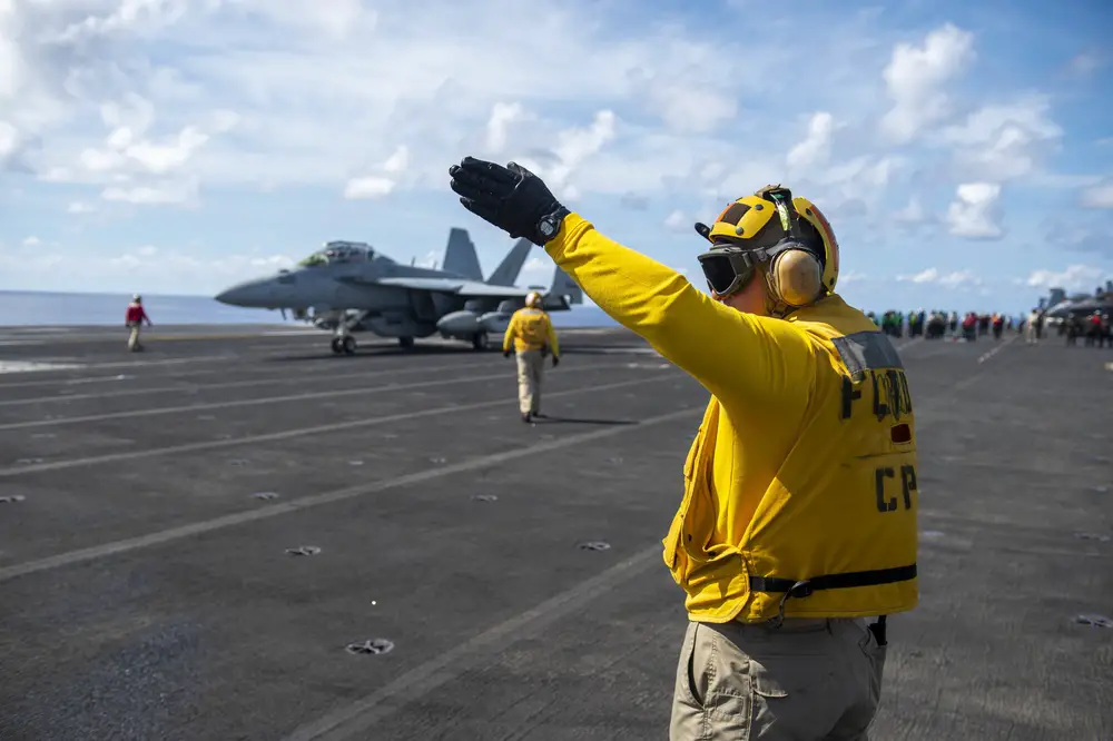 A Sailor directs an EA-18G Growler, assigned to the “Gauntlets” of Electronic Attack Squadron (VAQ) 136, from the flight deck of Nimitz-class aircraft carrier USS Carl Vinson (CVN 70)