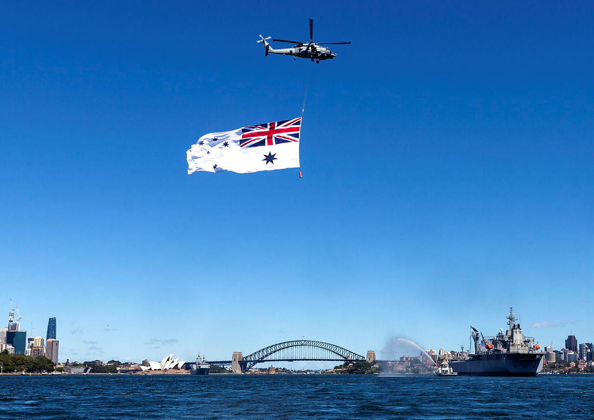 An MH60-R helicopter from 816 Squadron flies over HMAS Sirius during its final lap of Sydney Harbour.