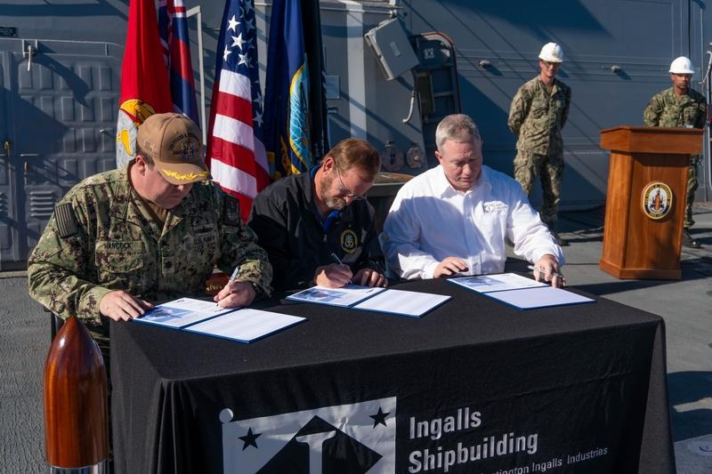 Signing ceremonial documents declaring delivery of Frank E. Petersen Jr. (DDG 121) from Ingalls Shipbuilding to the U.S. Navy are, from left, Navy Cmdr. Daniel Hancock, prospective commanding officer DDG 121; Billy Oaks, superintendent, Aegis Combat System, Supervisor of Shipbuilding, Gulf Coast; and Donny Dorsey, Ingalls DDG 121 ship program manager. In the background are Cmdr. Sean Doherty, left, DDG program manager’s representative; and Chief Petty Officer Yamina Bolar, DDG 121 chief Aegis fire controlman.