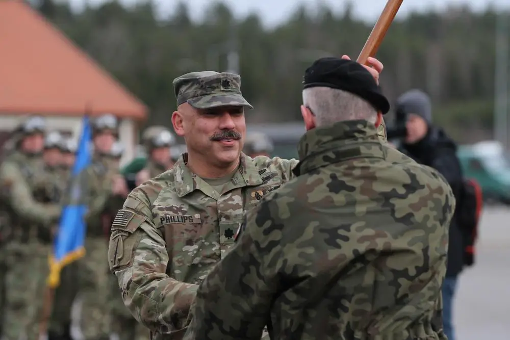 U.S. Army Lt. Col. Trevor Phillips, center, commander of 1st Battalion, 185th Infantry Regiment, accepts the NATO guidon from Plk. (Col.) Piotr Fajkowski, Polish commander of the 15th Mechanized Infantry Brigade, Feb. 11, 2022, signifying the 185th’s official command of Battle Group Poland at the hand over, take over ceremony at Bemowo Piskie Training Area, Poland.