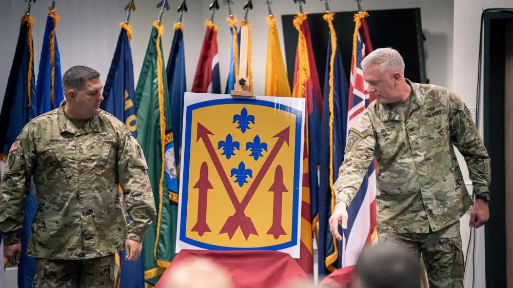 U.S. Army Col. Bruce Bredlow, commander, 52nd Air Defense Artillery Brigade and Master Sgt. Gregory Irvine, senior enlisted advisor, 52nd Air Defense Artillery Brigade, reveals the shoulder patch insignia for the new brigade during a ceremony Oct. 6 on Sembach Kaserne, Germany. 