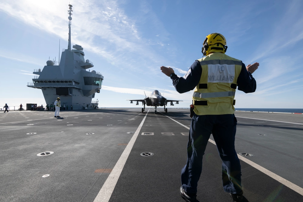 An HMS Prince of Wales aircraft handler marshals an F-35B Lightning II on the flight deck of the U.K.'s newest aircraft carrier Nov. 5, the last day of F-35 flight trials aboard Britain's biggest warship. (Photo by Michael D. Jackson)