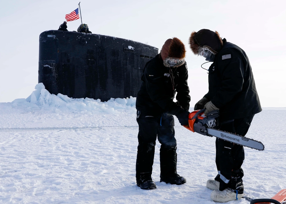 Field technicians assigned to the Arctic Submarine Laboratory prepare to remove ice from the Los Angeles-class attack submarine USS Hampton (SSN 767) at Ice Camp Whale on the Arctic Ocean, during Ice Camp (ICE CAMP) 2024.