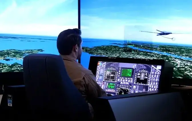 A Boeing F/A-18 systems pilot demonstrates the Manned-Unmanned Teaming (MUM-T) capability from his simulator cockpit. The Boeing-led team virtually demonstrated an F/A-18 pilot commanding an unmanned MQ-25 to release a refueling drogue and refuel the Super Hornet, using existing communications links on both platforms. (Photo by Boeing)