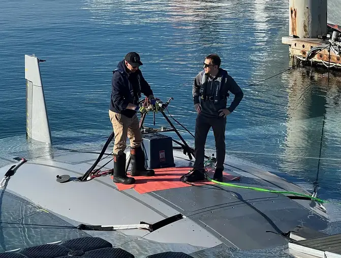 DARPA program manager Dr. Kyle Woerner (right) talks with a member of the Northrop Grumman team while standing atop the Manta Ray vehicle.