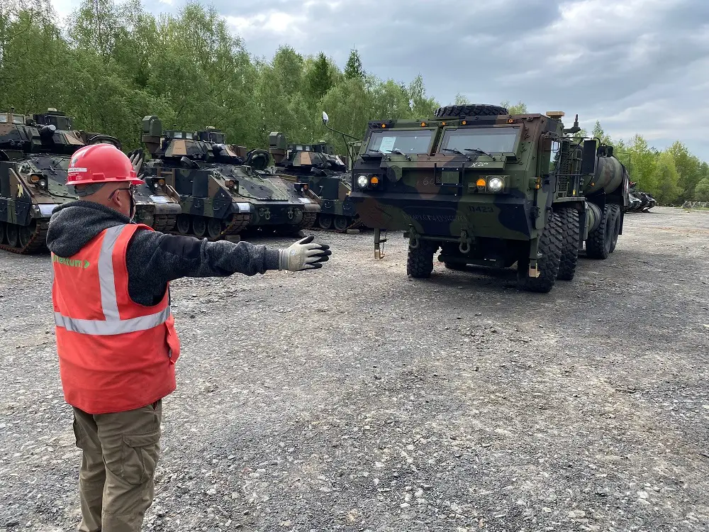 A contractor from the Coleman Army Prepositioned Stocks-2 worksite in Mannheim, Germany, ground guides an M978 heavy expanded mobility tactical fueler at an Equipment Configuration and Hand-off Area in Libava, Czechia, during DEFENDER 24, May 2.