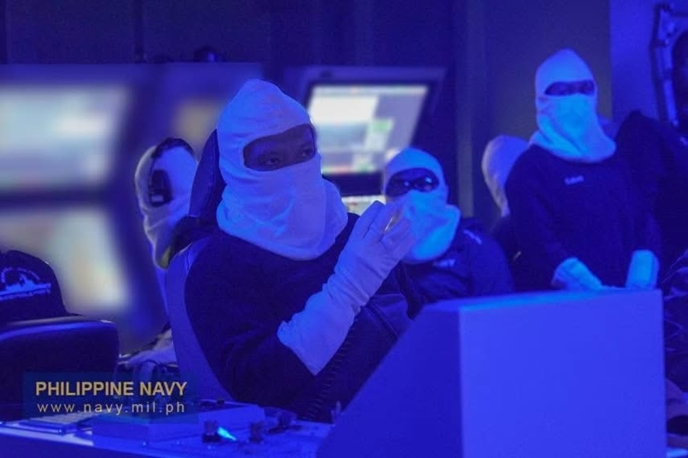 A front-on shot taken in the blue-lit Combat Information Center (CIC), showing a Philippine Navy sailor from the chest up.